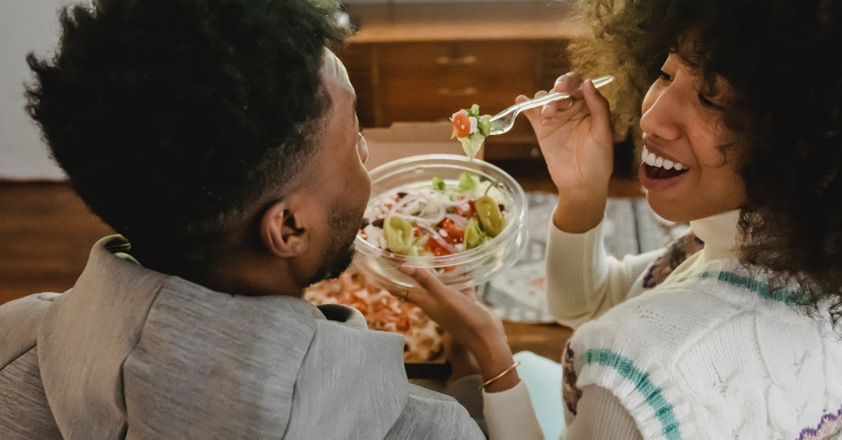 Why does Prince T'Challa have a 6-sided TV in "Black Panther"? - Happy young ethnic woman feeding boyfriend with salad while sitting on couch