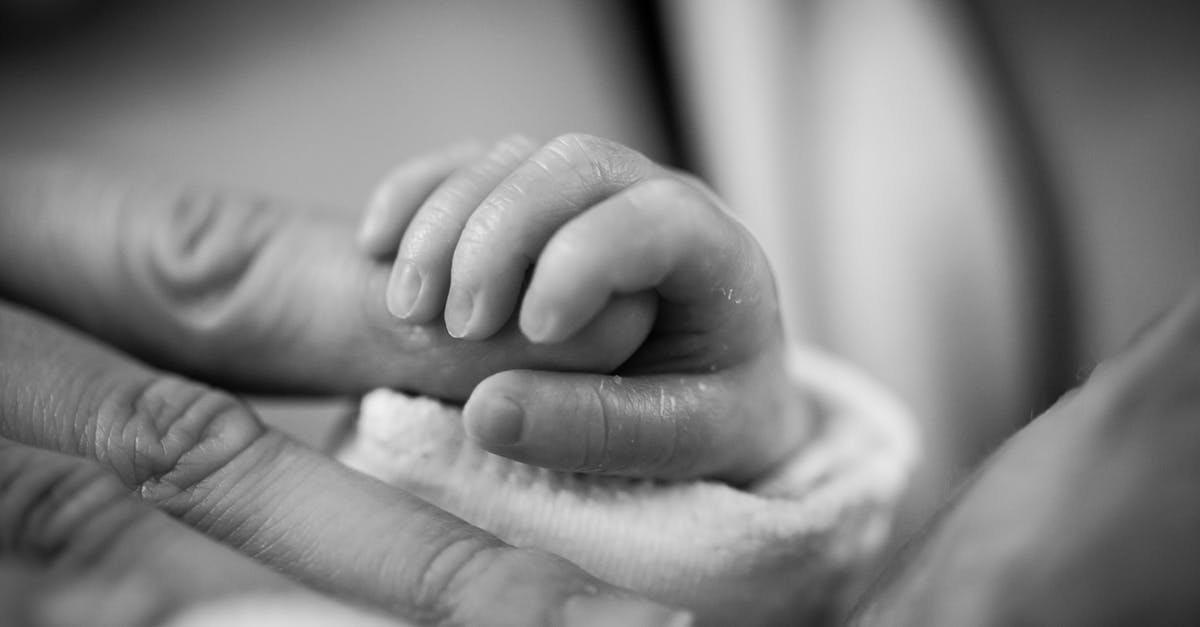 Why does she give birth to a dog-headed baby? - Grayscale Photography of Baby Holding Finger