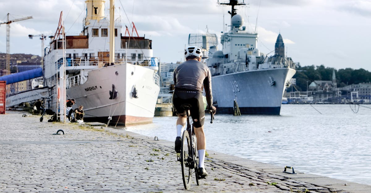 Why does the Australian Navy use Revolutions XX00? - Man in Black T-shirt Riding Bicycle on Gray Concrete Pavement Near White and Blue Ship