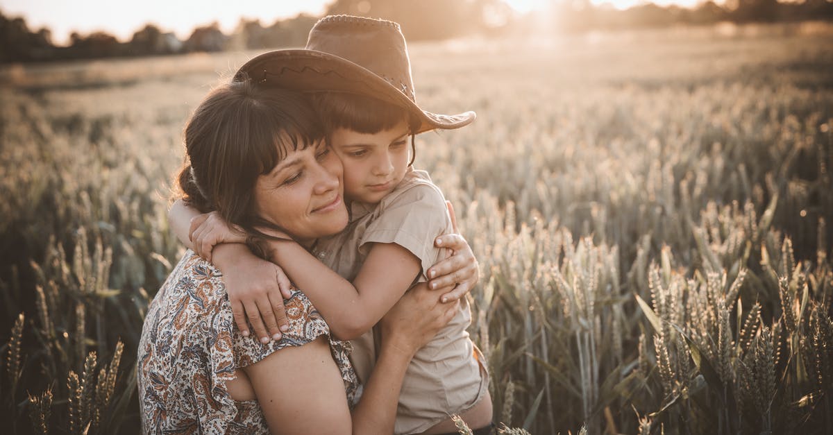 Why does the cowboy stab the woman in Unforgiven? - Gentle mom with closed eyes hugging son wearing cowboy hat in rural wheat field at sunset