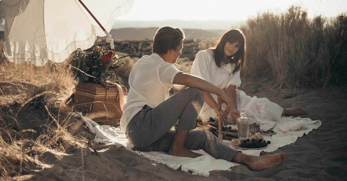 Why does the drink affect him? - Young loving couple having romantic picnic sitting on white blanket with food and drinks under white umbrella