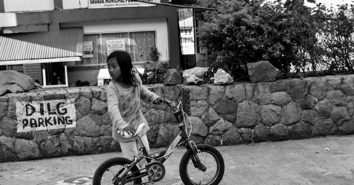 Why does the Station Inspector chase children who are on their own and threaten to send them to an Orphanage? - Grayscale Photo of Girl Holding Bike