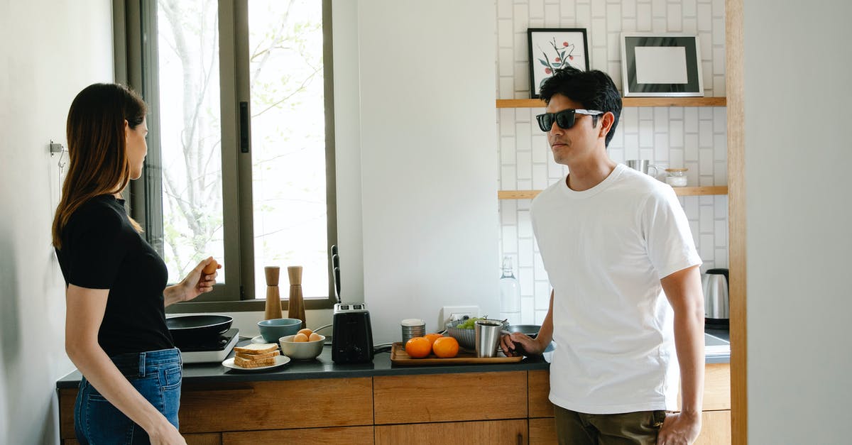 Why does the tenant with the sick wife say "If I believed that, I would never have opened the door."? - Young Asian man with vision loss in black glasses standing in kitchen with wife preparing breakfast while spending morning together at home