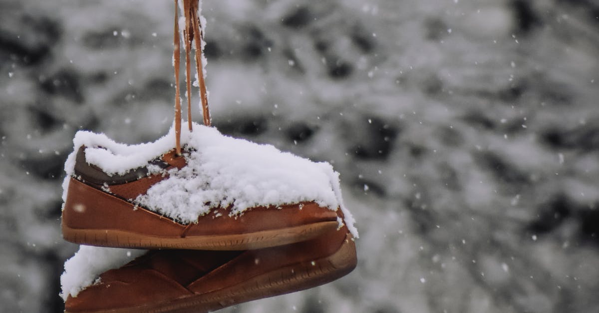 Why does the Winter Warlock lose his powers? - Brown old fashioned footwear covered with snow hanging on rope against leafless trees on blurred background on cold winter day