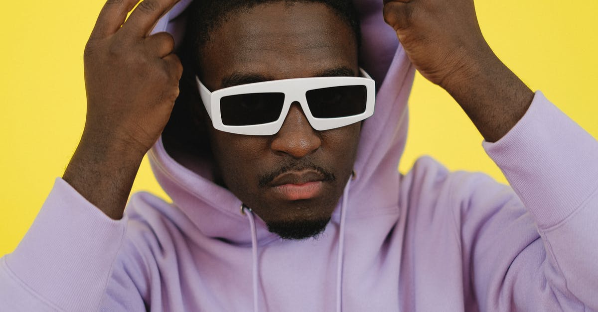 Why does this cameo character look like this? - Trendy African American male in stylish white sunglasses putting on hood and looking at camera against yellow background