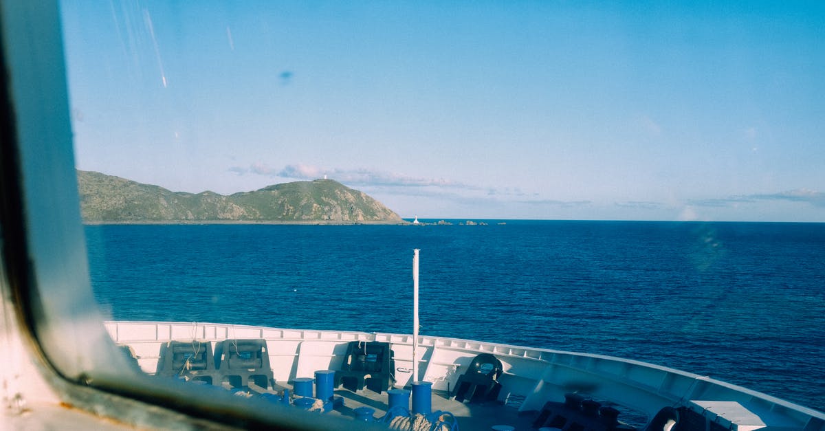 Why does U96 sail through the sea near Gibraltar? - Through window of modern vessel floating on rippling sea against blue sky with rocky mountain in distance in coastal terrain