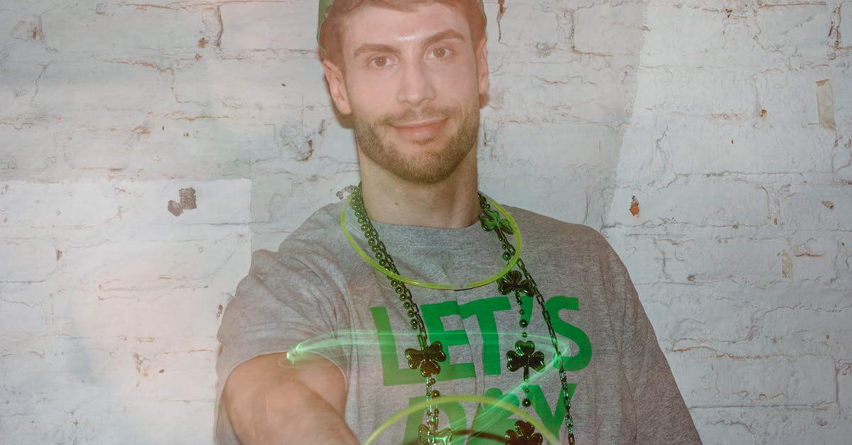 Why doesn't the Green Lantern ring do this? - Through glass wall view of friendly adult male in beads looking at camera while twirling plastic ring while celebrating Saint Patrics day