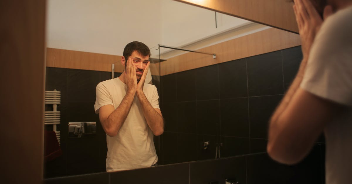 Why doesn't the reflection match the man? - Tired man looking in mirror in bathroom