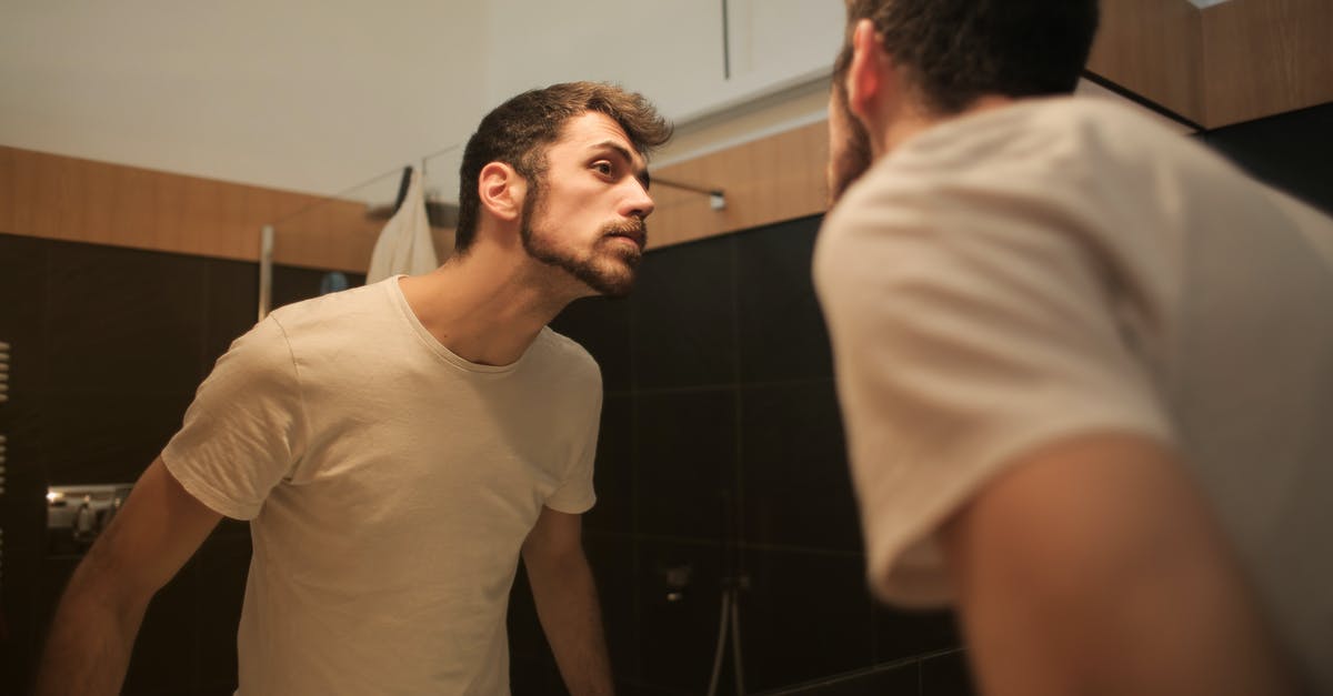 Why doesn't the reflection match the man? - Stylish concentrated man looking in mirror in bathroom