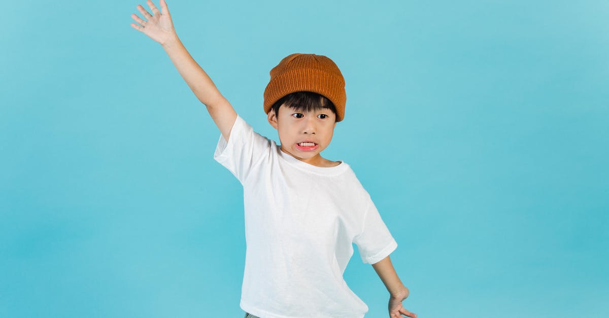 Why doesn't Voldemort have a nose? - Astonished stylish Asian boy wearing hat and white t shirt looking away while standing with outstretched arms in light studio