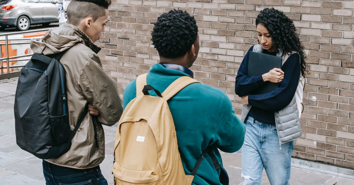 Why is Hanna so snappish and rude to Michael at times? - Young multiracial male friends with backpacks offending female with folder on city street near brick wall in daylight