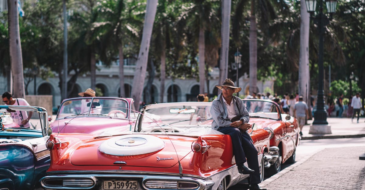 Why is Havana covered in 5-digit numbers in Our Man in Havana? - A Man Sitting on Red Vintage Car