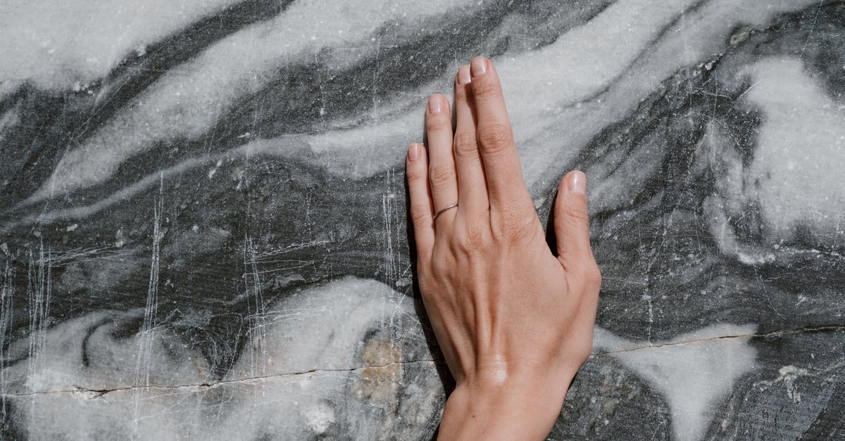 Why is Isabella Hartley not turned to stone instantly when she touches the obelisk? - Person's Hand Touching a Marble Surface