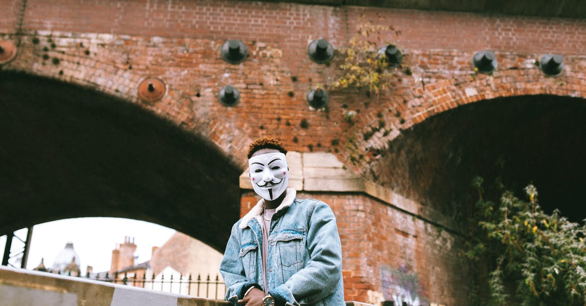 Why is it a problem for Freddie if the guys from Munich did what he wanted? - Black man in Anonymous mask standing against brick construction