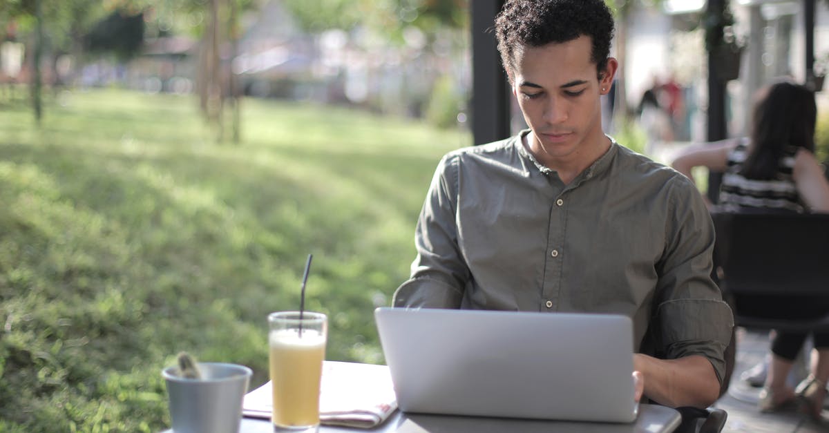 Why is it always the same type of beer cup used in college-style movies/series? - Focused black male freelancer using laptop in street cafe