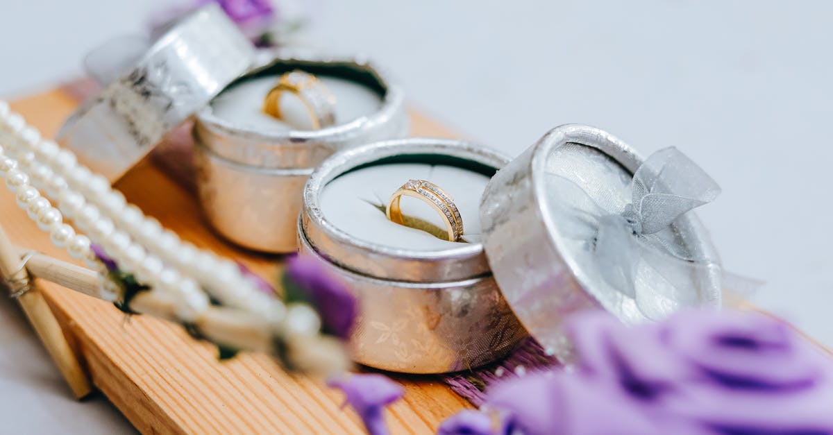 Why is the purple wedding called purple wedding? - Golden wedding rings in small grey boxes on wooden stand with purple flowers
