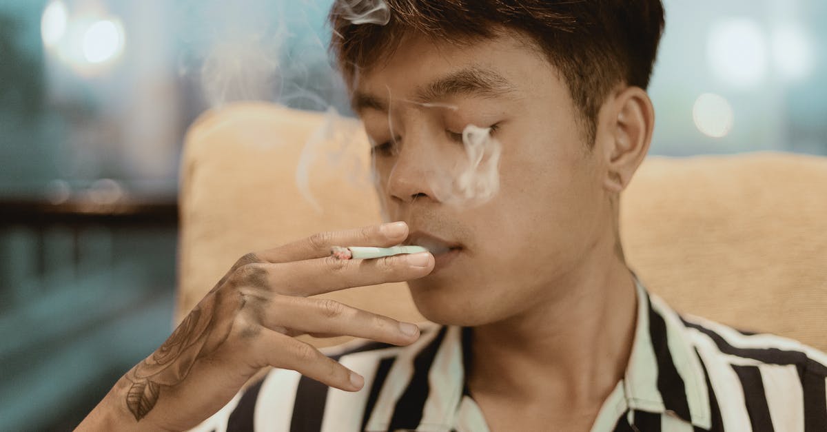 Why is there an umbrella man in this Breaking Bad song? - Thoughtful young ethnic male in striped shirt with tattoo on hand smoking while resting in chair in street cafe on blurred background