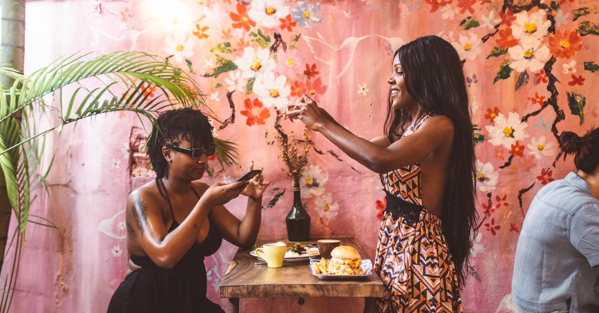 Why is this picture used in the opening titles of Cheers, and where is it from? - Side view happy African American females in stylish dresses taking photos on smartphones of freshly cooked food while having lunch in cozy cafe against painted wall