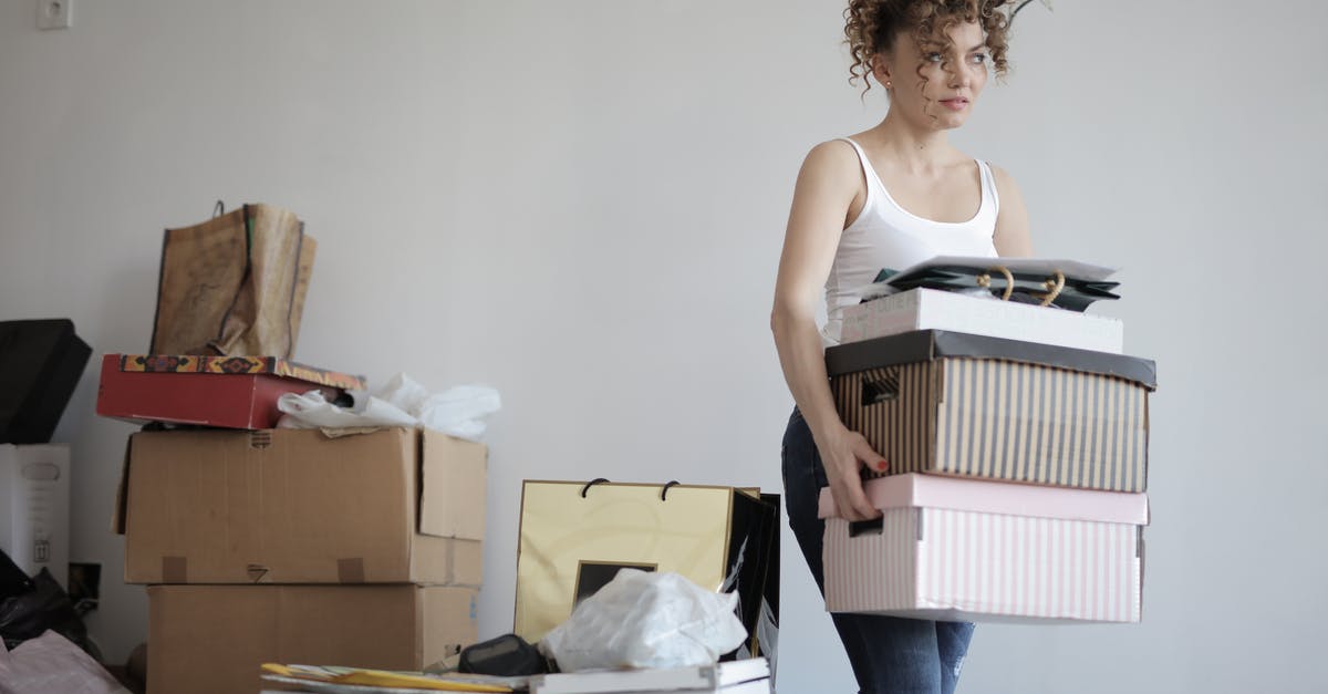 Why not sell the stuff instead of throwing away? - Concentrated woman carrying stack of cardboard boxes for relocation