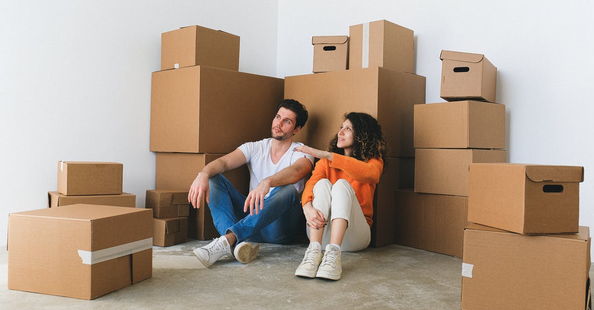 Why not sell the stuff instead of throwing away? - Full body of young happy couple in casual clothes sitting on floor leaning on stack of cardboard boxes and chatting after relocation in new flat