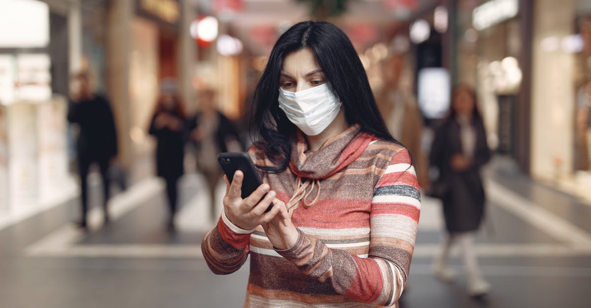 Why take that "glass floor" risk in the museum? - Young female customer in striped wear and protection mask on face using smartphone while standing in shopping mall during coronavirus pandemic
