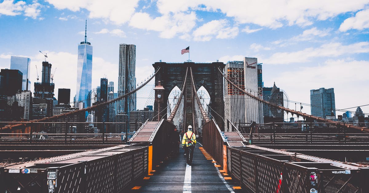 Why there are construction cranes on apparently completed buildings in New York? - Man Walking on Bridge