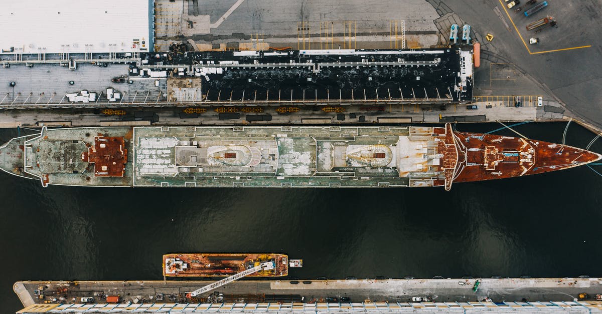 Why was District 9 alien ship stuck for so long? - Drone view of long ship moored on water of river near pier in daytime