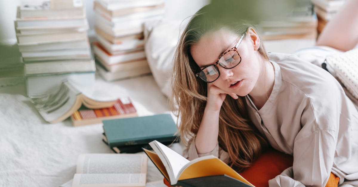 Why was Dragonstone left unoccupied for such a long period of time? - Concentrated young female in eyeglasses reading book while lying on white blanket near heap of literature in light room at home