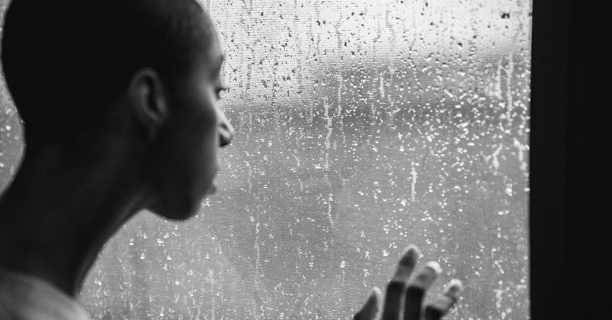 Why was Elizabeth in the rain and alone? - Thoughtful androgynous black woman standing near window at rainy day