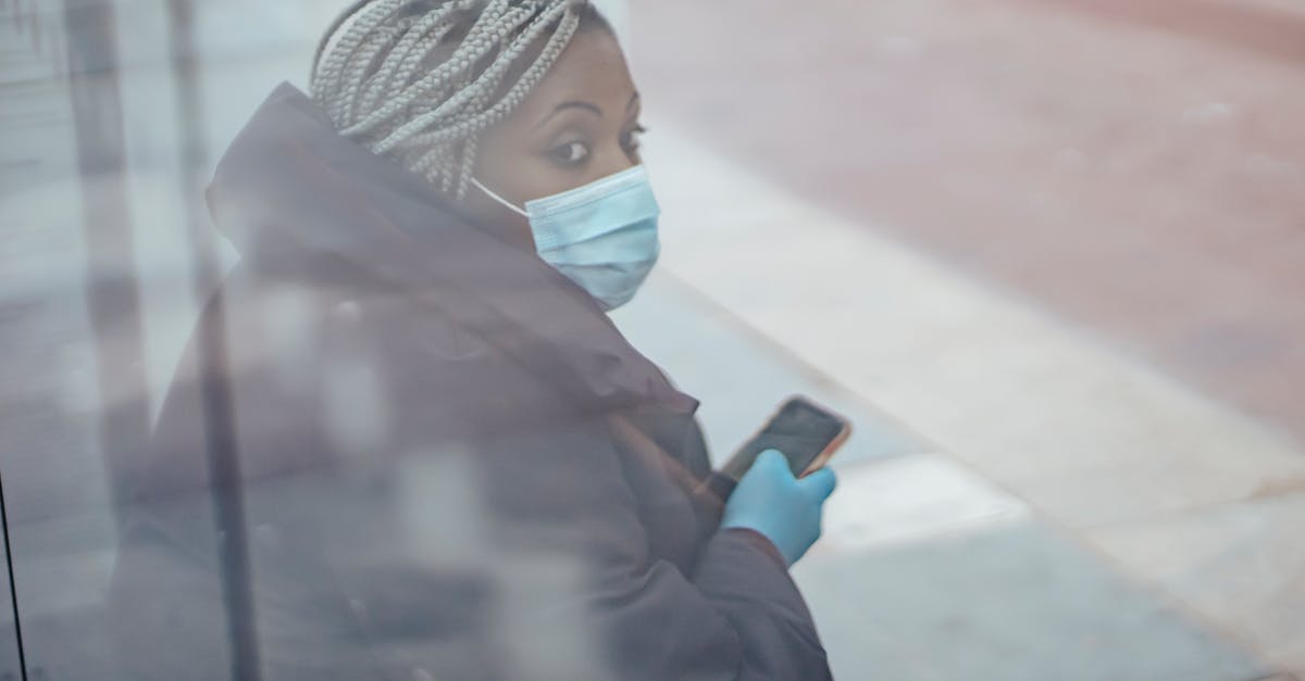 Why was the doctor left alive in the bus? - Through glass wall side view of mature ethnic female medic in outerwear with cellphone looking away in town
