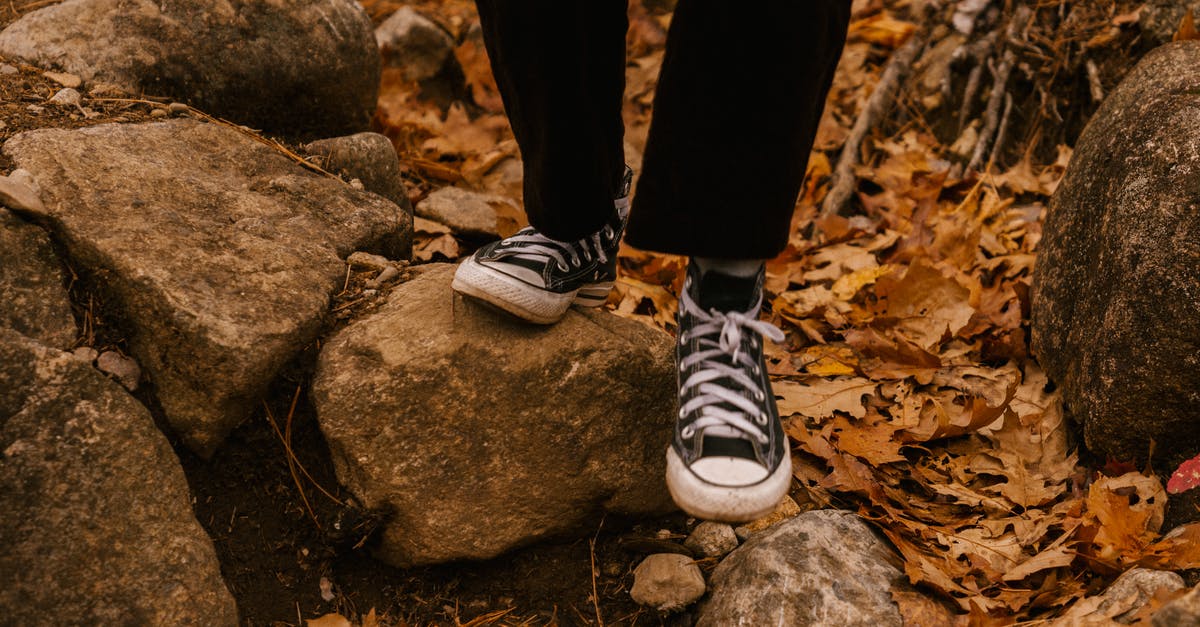 Why was this character in A Quiet Place Part II able to walk with shoes? - Crop legs of unrecognizable person in sneakers and black trousers walking on stones in autumn forest