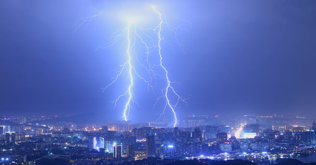 Why we can see little light even after main power is off? - Breathtaking thunderstorm with lightning bolts over modern illuminated city at night with purple sky