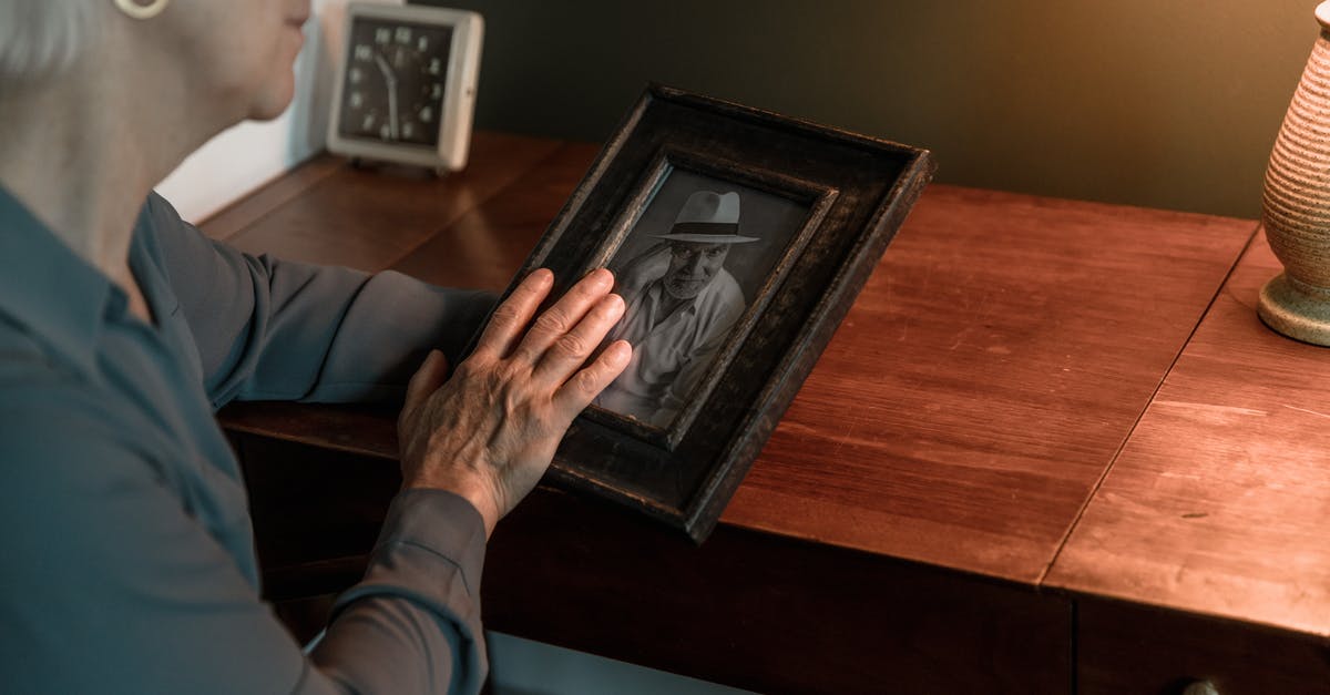Why were some emotional displays tolerated in Equilibrium? - Person in Blue Long Sleeve Shirt Holding Black Wooden Picture Frame