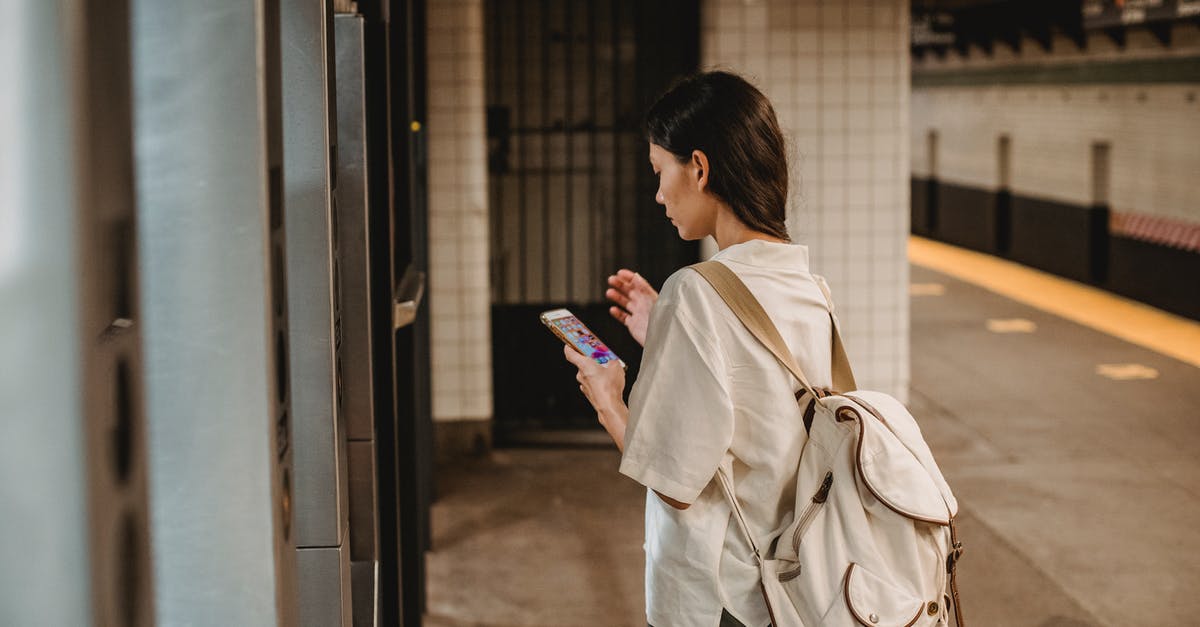 Why would an advanced alien use a subway train to get into the city? - Side view of young concentrated ethnic female in casual clothes and backpack browsing mobile phone while standing on platform of subway station