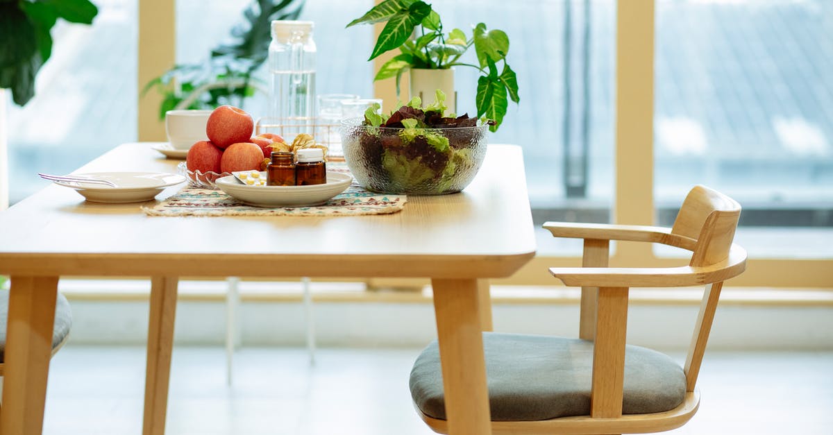Why would the healthy Anne Welles need pills? - Plates with medicines and ripe apples and bowl of fresh lettuce salad placed on wooden table near potted plant and bottle of water