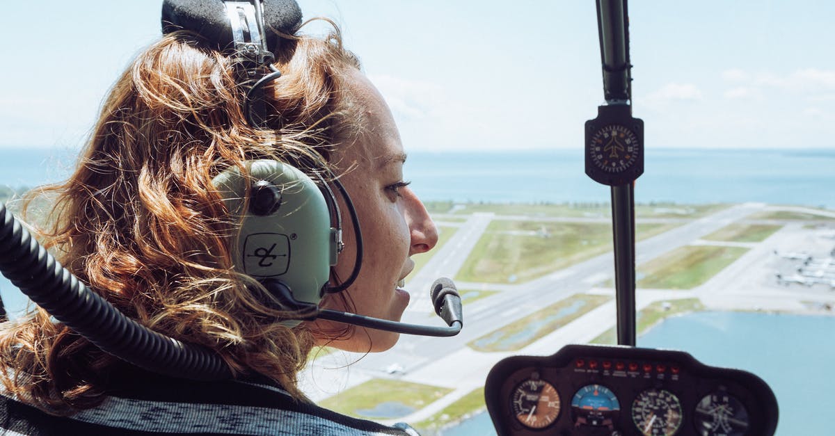 Would the crew have made it back to Earth anyway? - Back view of positive young female traveler in casual wear and headset sitting in cockpit of modern helicopter during flight over coastal town