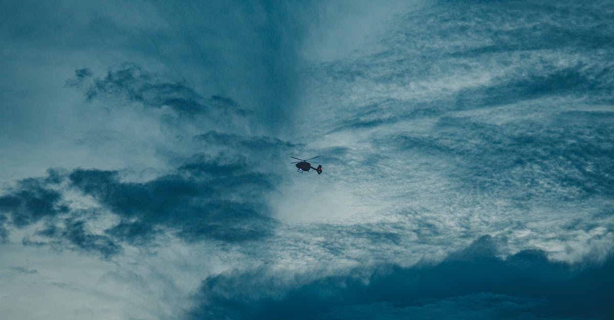Would the helicopter sacrifice scene from London Has Fallen actually happen? - From below silhouette of distant helicopter with propeller flying in gloomy sky with floating fluffy clouds at sunset time in nature
