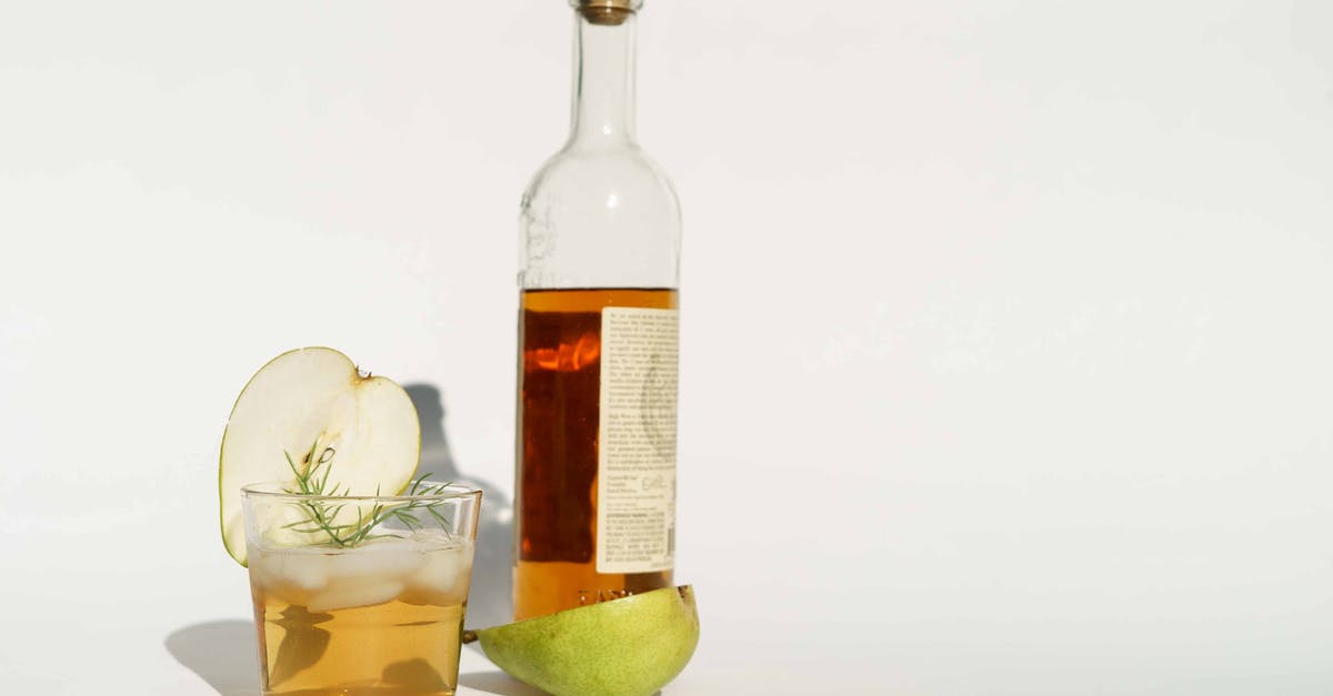 Wouldn't both glasses of brandy have "tasted a bit shit"? - Glass bottle of calvados with halved pear and rosemary sprigs placed on white background