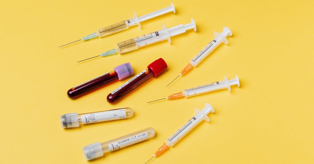 Yellow substance being consumed - From above composition with medical syringes of different sizes arranged with test tubes filled with blood samples placed on yellow surface